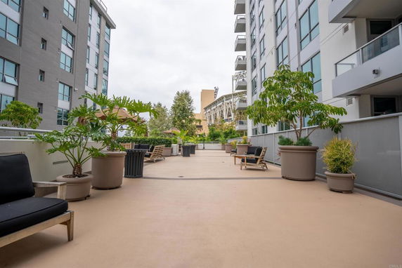 Outdoor area between two buildings with potted plants and seating, overlooking surrounding structures.