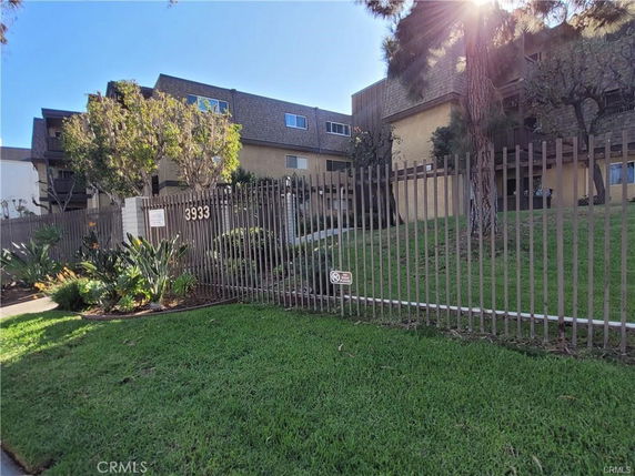 Front view of a multi-story residential building with a fenced yard.