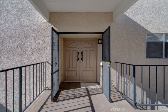 Entrance view of a beige house with a secured gated door and cream-colored main door.