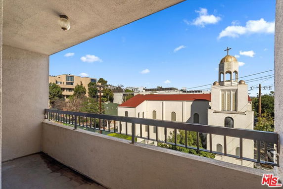 View of surrounding areas from a balcony showing a church with a cross-shaped bell tower and nearby buildings.