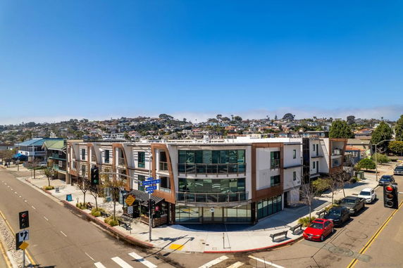 Front view of a modern multi-story building on a street corner.