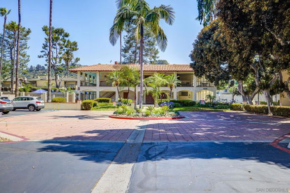 Front view of a two-story building with a tiled roof and surrounding palm trees.