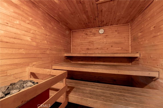 Interior view of a wooden sauna room with tiered benches and a wall thermometer.