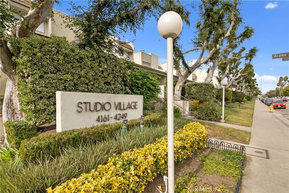 Front view of Studio Village complex with a walkway and greenery.