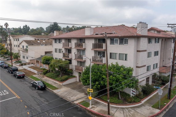 Front view of a multi-story apartment building with a tiled roof and balconies.