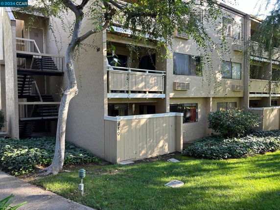 Front view of a multi-story apartment building with balconies and stairs.