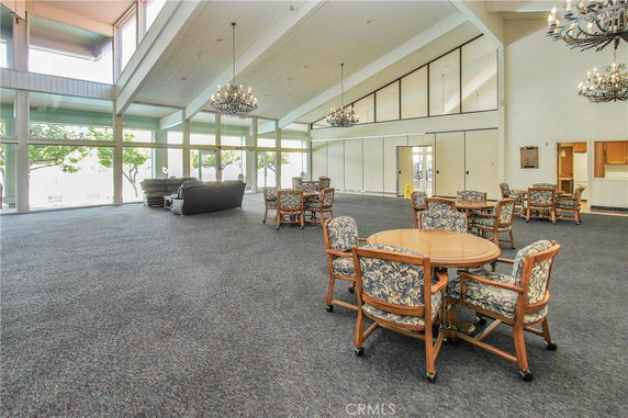 Spacious indoor area with tables and chairs, large windows, and chandeliers.