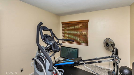 Room with exercise equipment and a fan.