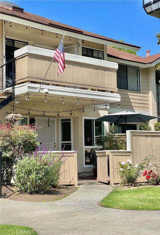 Front view of a two-story house with a balcony and American flag.