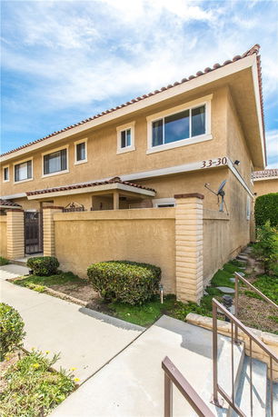 Front view of a two-story house with a gated entrance and beige exterior.