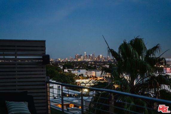 Panoramic city view from a rooftop with urban landscape and distant skyline.