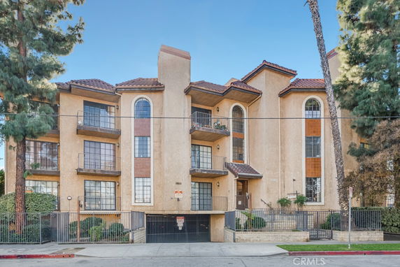 Front view of a multi-story apartment building with balconies and large windows.