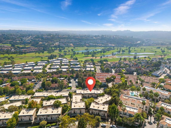 Aerial view of a residential area with multiple buildings and a golf course in the background.