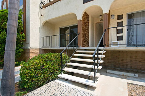 Front view of a multi-story building with stairs leading to the entrance.