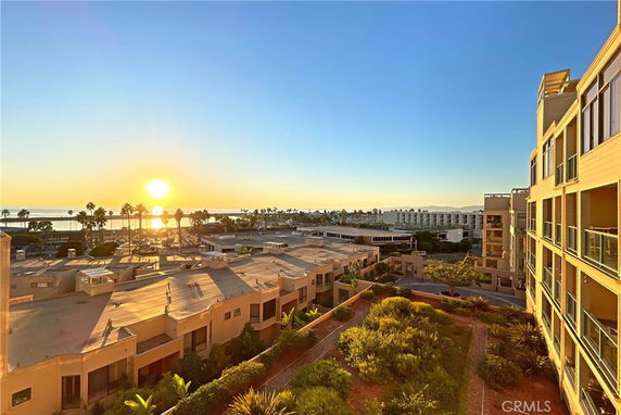 Panoramic view of a coastal area with buildings and the ocean at sunset.