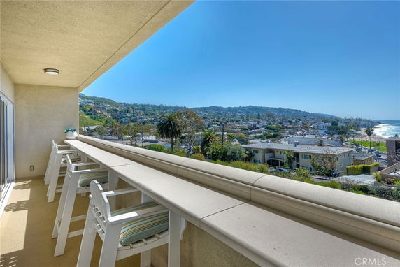 Balcony view overlooking a coastal area with hills and ocean in the background.