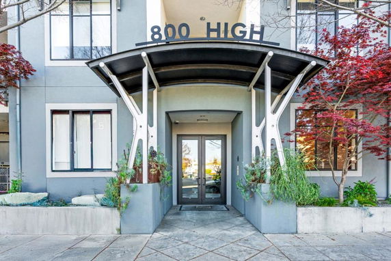 Front view of a modern building entrance with a metal canopy and large windows.