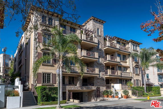 Front view of a multi-story residential building with balconies and stone facade.