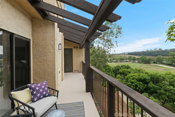 Balcony view overlooking a landscaped area with trees and hills in the distance.