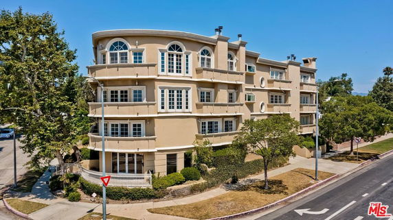 Front view of a multi-story residential building with balconies and large windows.