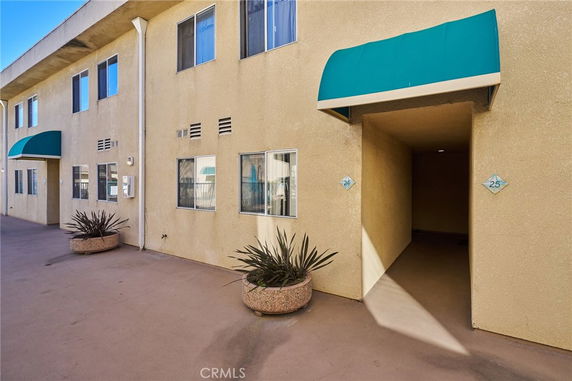 Front view of a beige multi-story building with green awnings and potted plants.