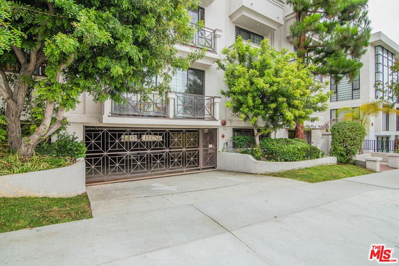 Front view of a multi-story residential building with balconies and a garage entrance.