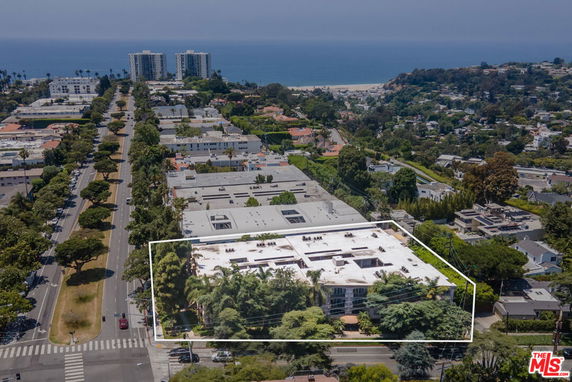 Panoramic aerial view of a neighborhood with buildings, roads, and distant ocean.