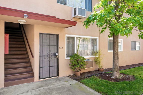 Front view of a residential building with a metal door and staircase.