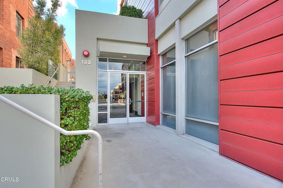Front view of a modern building entrance with large glass doors and red panels.