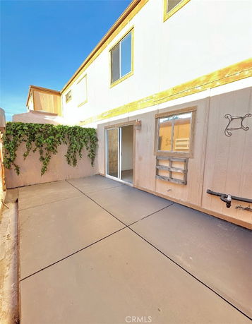 View of a building's exterior with sliding glass door and climbing plants.