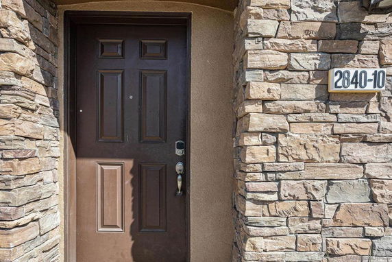 Front entrance of a building with a brown door and stone exterior.