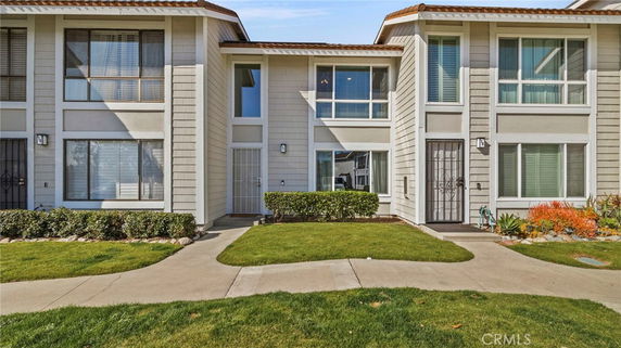 Front view of a modern two-story townhouse with large windows and a small garden area.