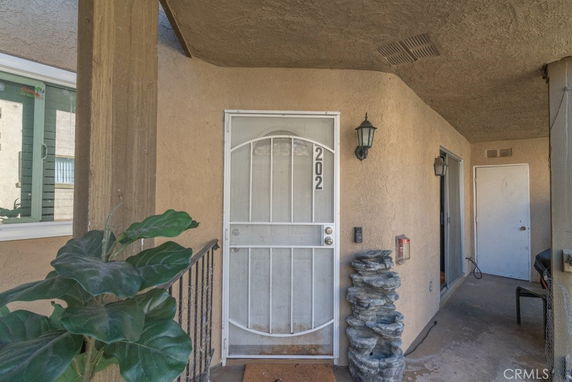 Entrance view of a residential unit with a metal door and exterior wall lighting.