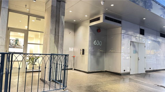 Front view of a building entrance with glass doors and a security gate.