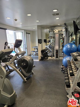 Indoor gym area with exercise machines and weights.