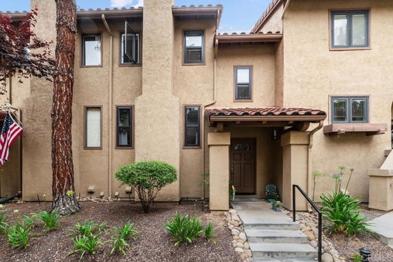Front view of a multi-story house with a tiled roof and stucco exterior.