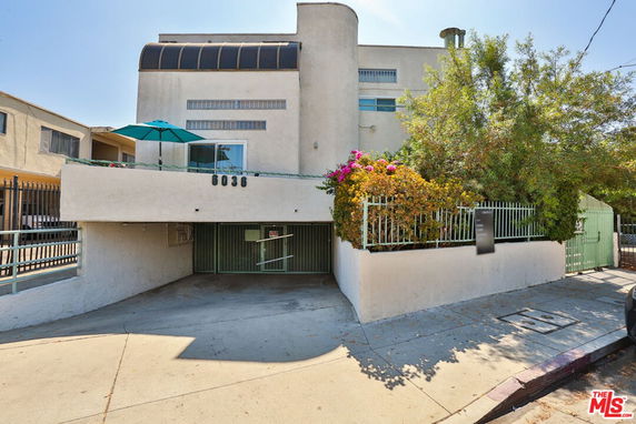 Front view of a multi-story building with a covered parking area and a balcony.
