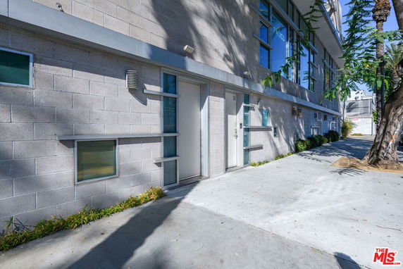 Front view of a modern building with large windows and a concrete pathway.
