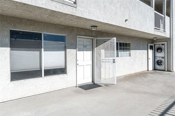 Front view of a two-story building entrance with door and large window.