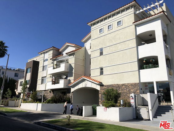 Front view of a multi-story residential building with balconies and archway entrance.