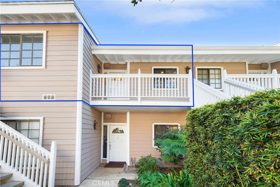 Front view of a two-story house with a balcony and white railing.