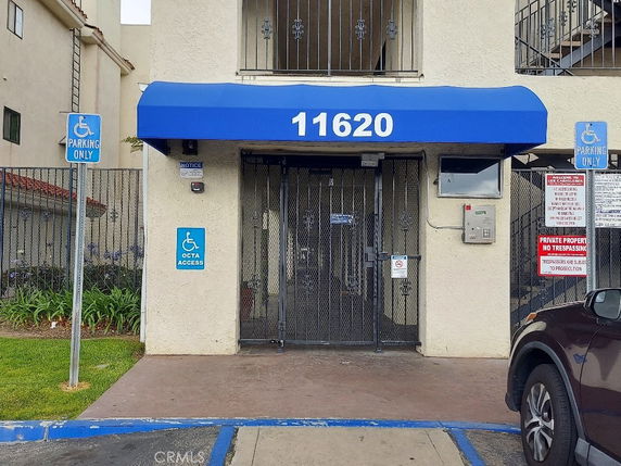 Front view of a building entrance with a blue canopy and accessibility signage.