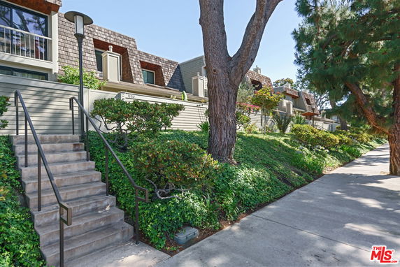 Front view of a multi-story residential building with a distinctive shingle roof and steps leading up to the entrance.
