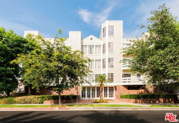 Front view of a multi-story residential building with a symmetrical design and large windows.