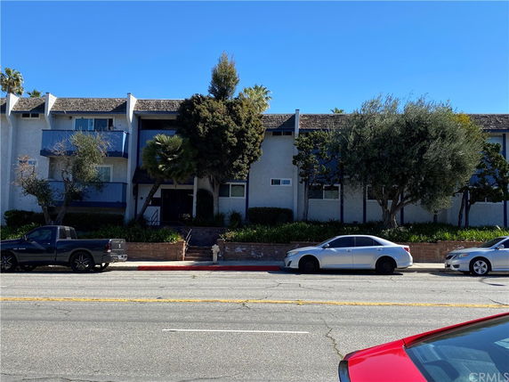 Front view of a multi-story building with trees and parked cars.