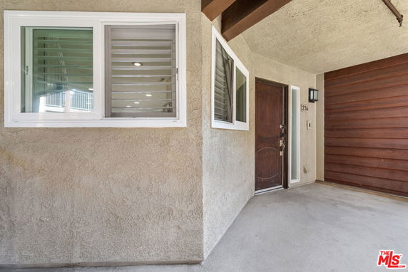 Entrance area of a building with a wooden door and windows.