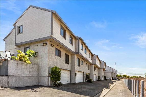 Side view of a multi-story residential building with garages on the ground level.
