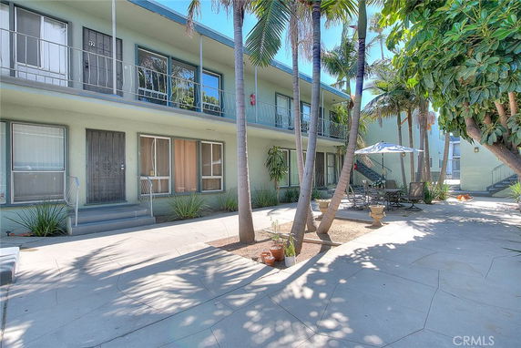Front view of a two-story residential building with balconies and outdoor seating area.