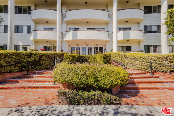 Front view of a multi-story building with balconies and a stairway entrance.