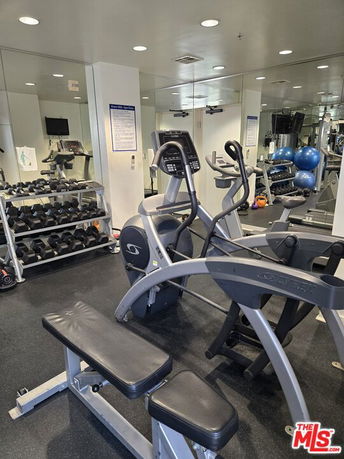 Indoor gym area with exercise equipment including elliptical machines and dumbbells.